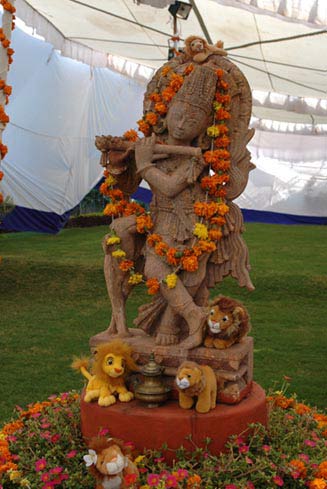 Krishna's statue is adorned with garlands and lions.